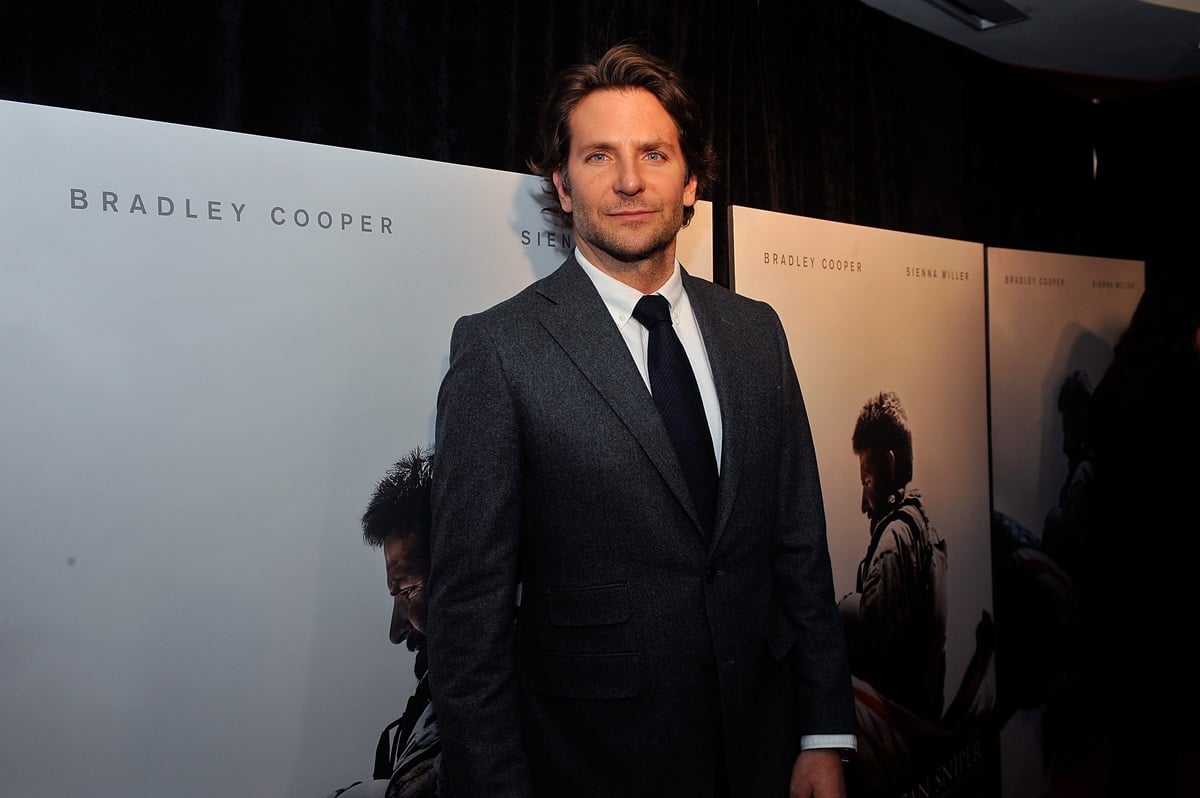 Bradley Cooper smirking in a suit at a premiere of 'American Sniper'.