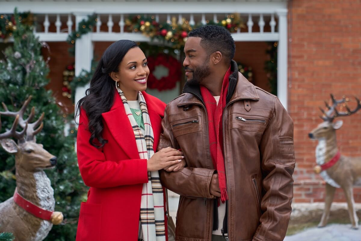 Woman in a red coat holding the arm of a smiling man in 'Christmas With a Kiss'