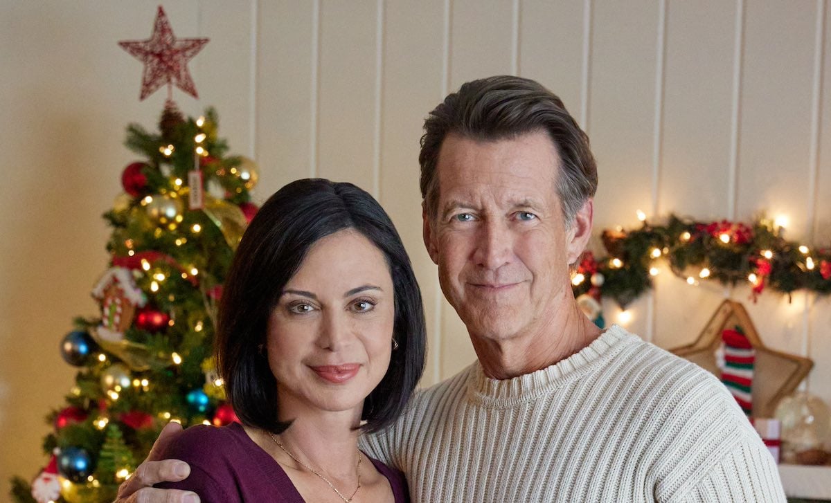 Catherine Bell standing next to James Denton in front of Christmas decorations in 'Christmas on Cherry Lane'