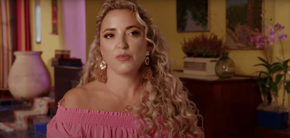 Daniele from '90 Day Fiance: The Other Way' with curly blond hair and wearing an off-the-shoulder pink top