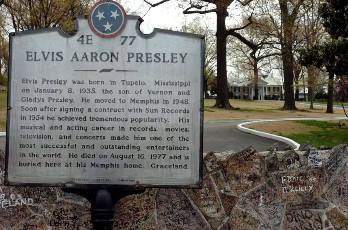 A sign gives a brief biography of Elvis sits in front of the drive up to Graceland.