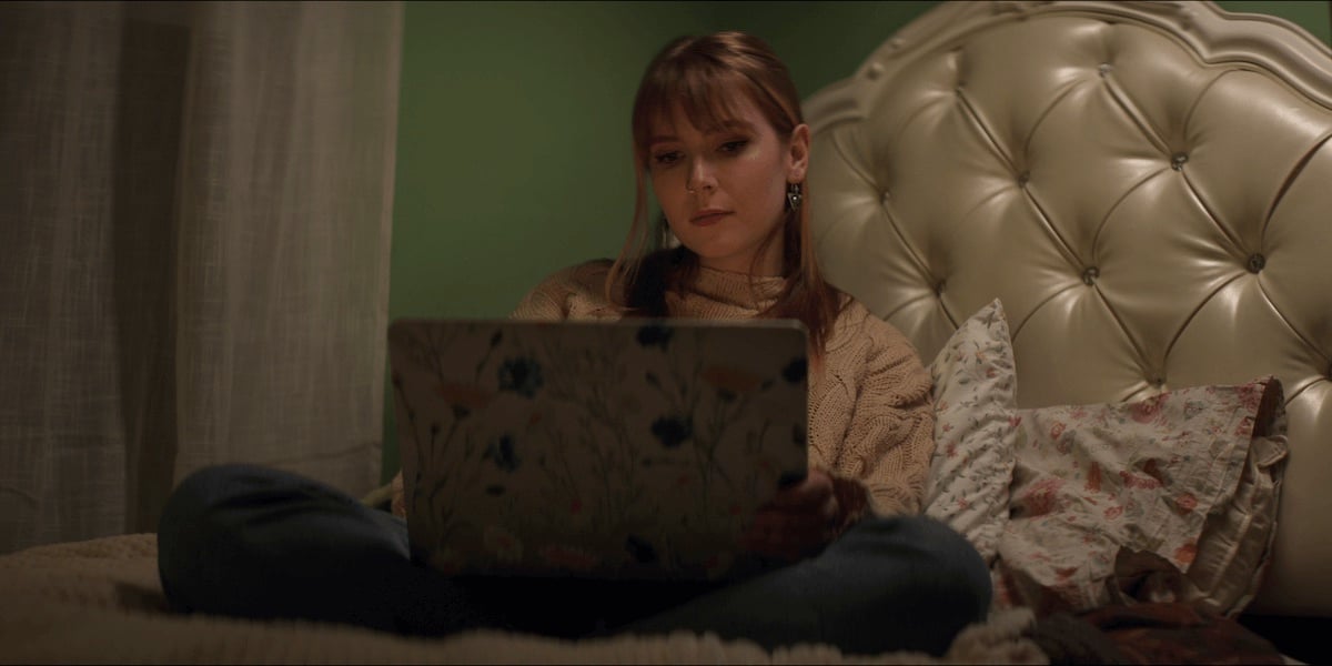woman sitting on a bed and looking at a laptop in Netflix's 'Escaping Twin Flames' docuseries