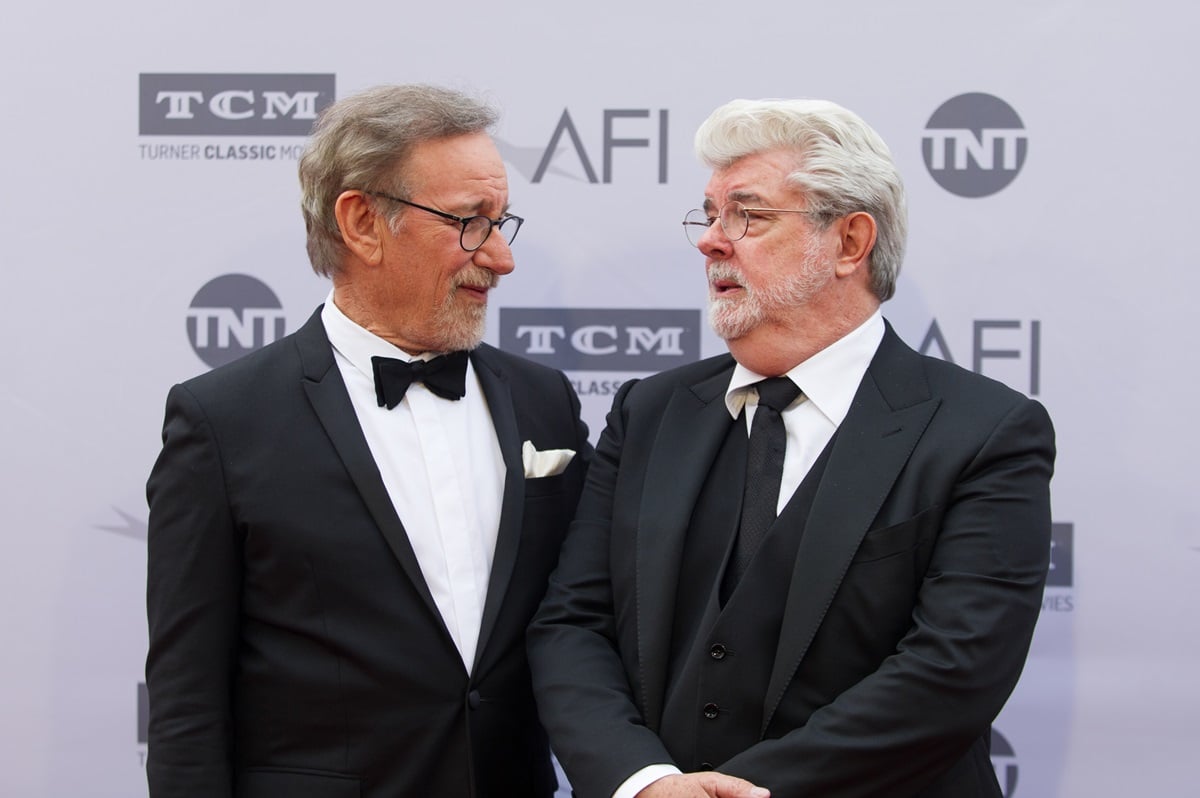 George Lucas and Steven Spielberg posing in suits at the 2016 American Film Institute Life Achievement Awards.