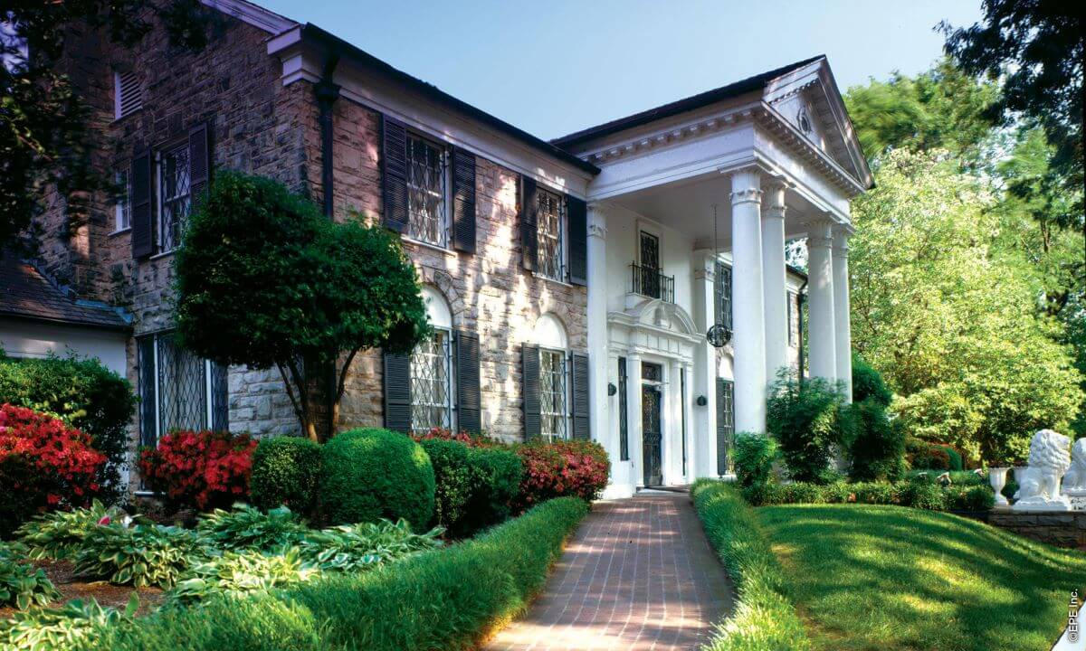 A photo of the outside of Graceland from the left side of the house's front. It is a sunny day.