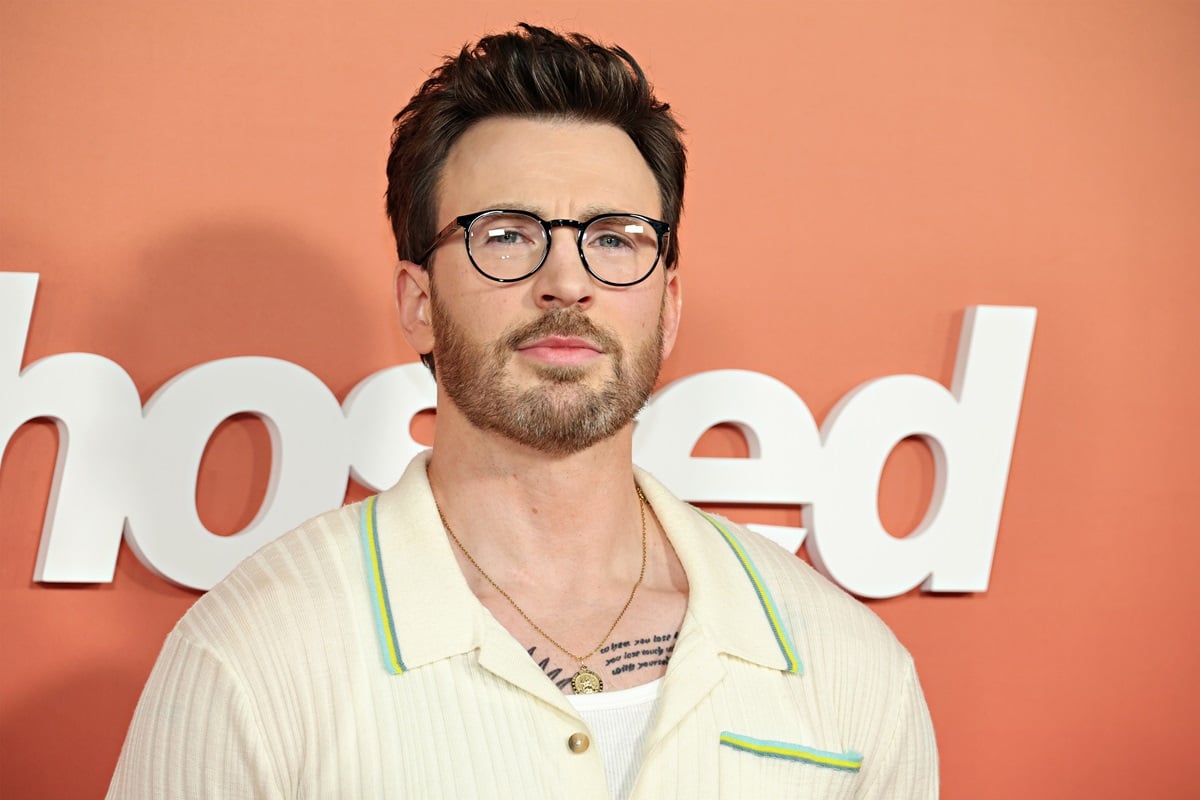 Chris Evans posing in a white sweater at the premiere of 'Ghosted'.