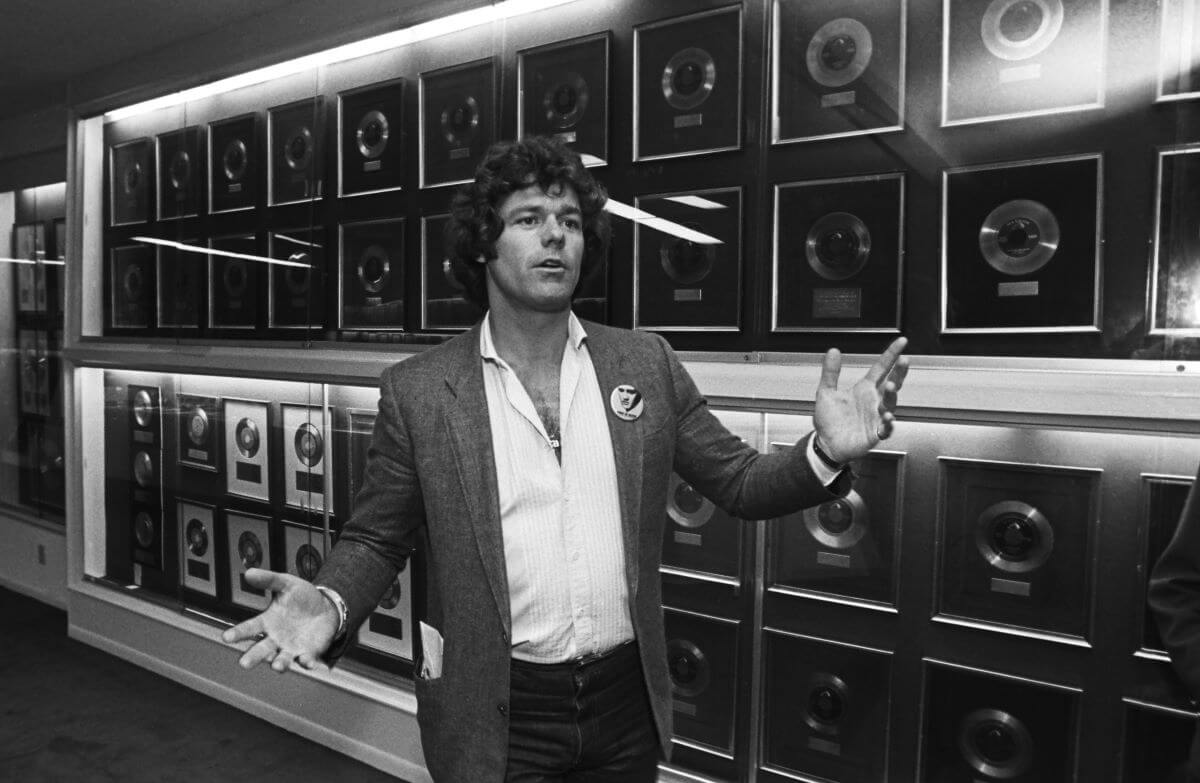 A black and white picture of Jerry Schilling standing in front of a wall of records.