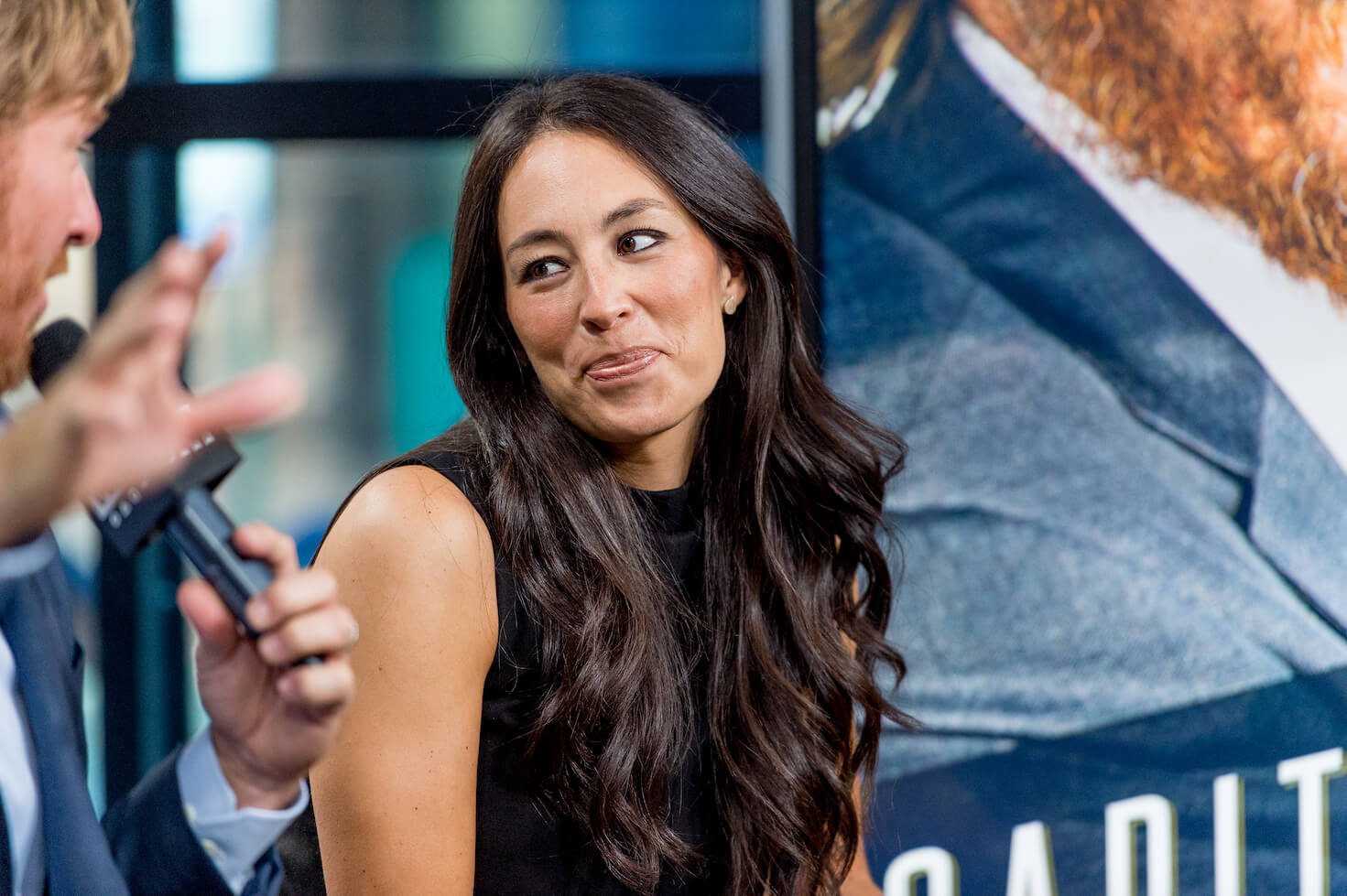 Joanna Gaines wearing a sleevless top at an event with Chip Gaines out of frame beside her