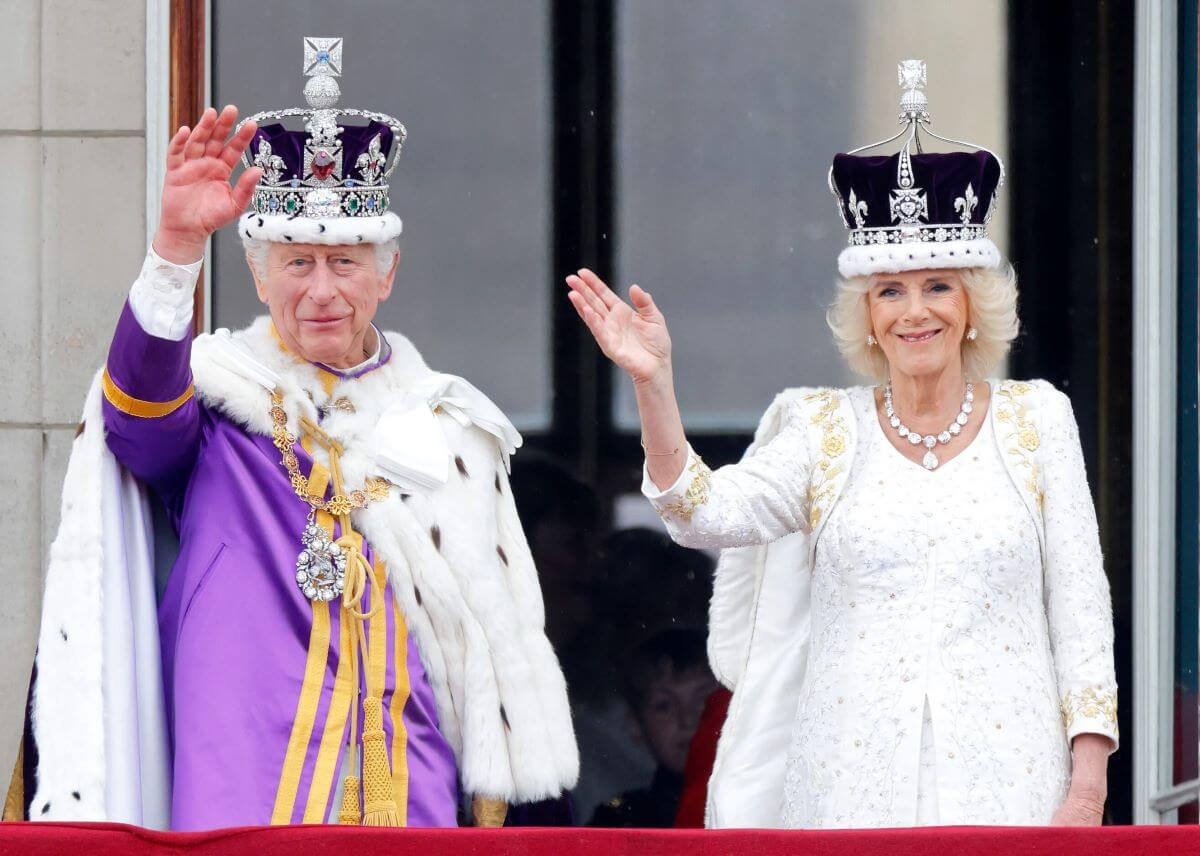 King Charles III and Queen Camilla wave from the balcony of Buckingham Palace, whilst watching an RAF flypast, following their coronation