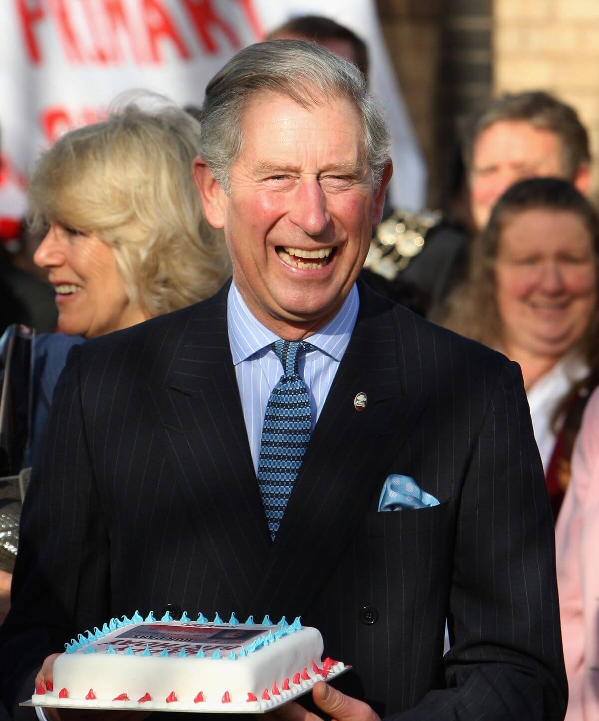 King Charles III holds a birthday cake he was given during his visit to Beckton Community Centre