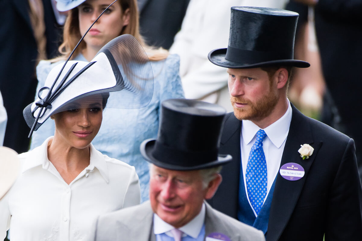 King Charles, who withdrew Prince Harry and Meghan Markle's transition funding, per a report, walks in front of the couple
