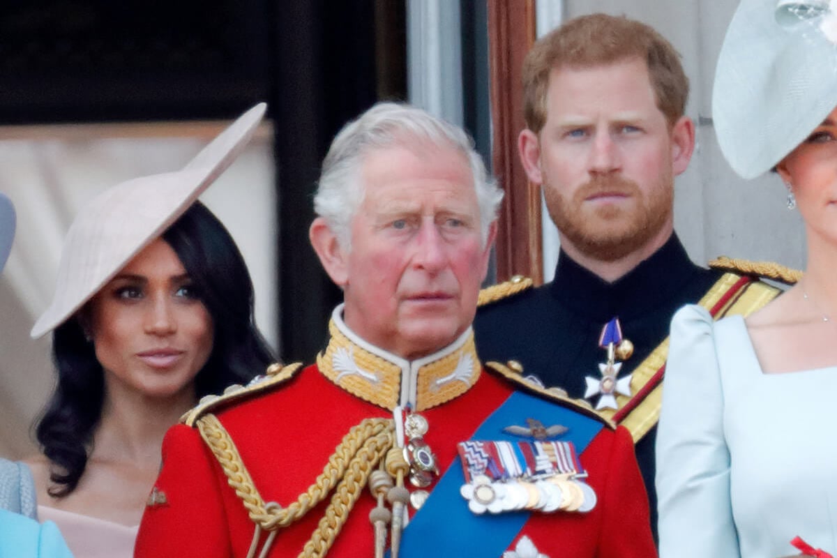 King Charles, whose been urged to try his son and daughter-in-law's strategy of appealing to people, stands in front of Meghan Markle Prince Harry.