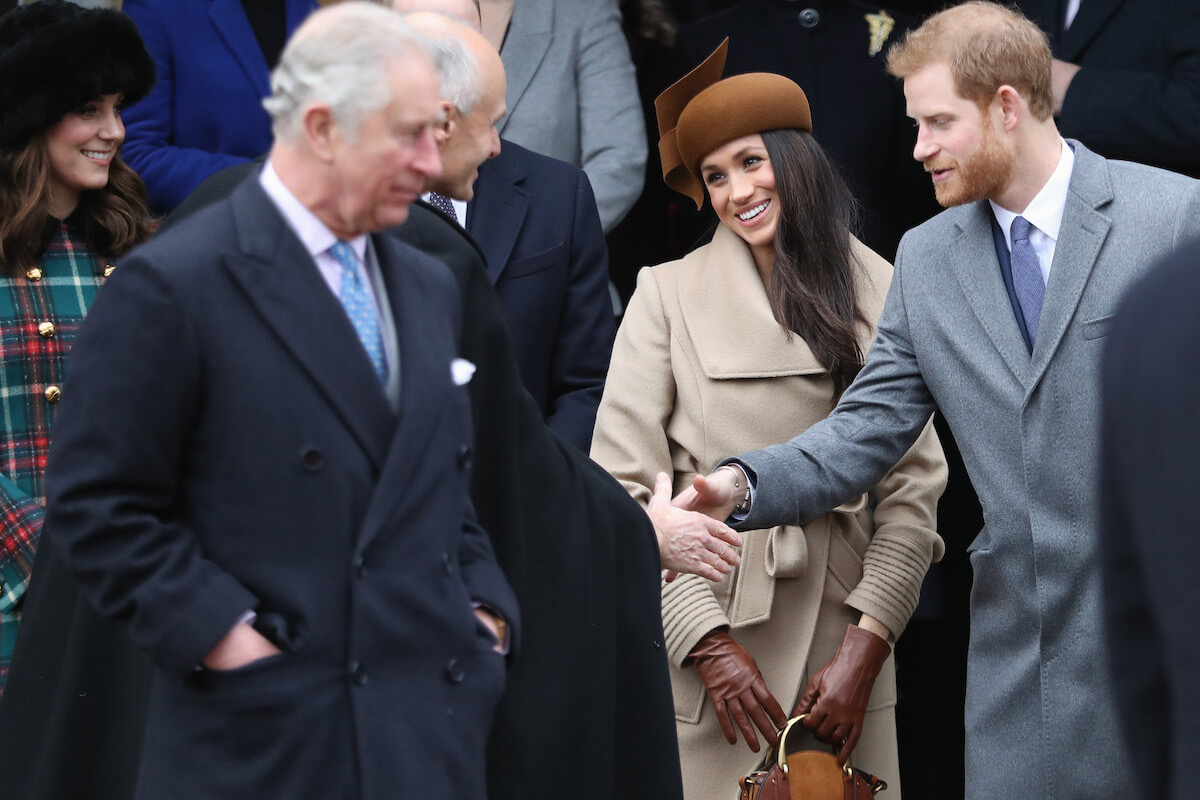 Meghan Markle and Prince Harry, whose names are banned from being mentioned at King Charles III's 75th birthday party, stand behind the monarch