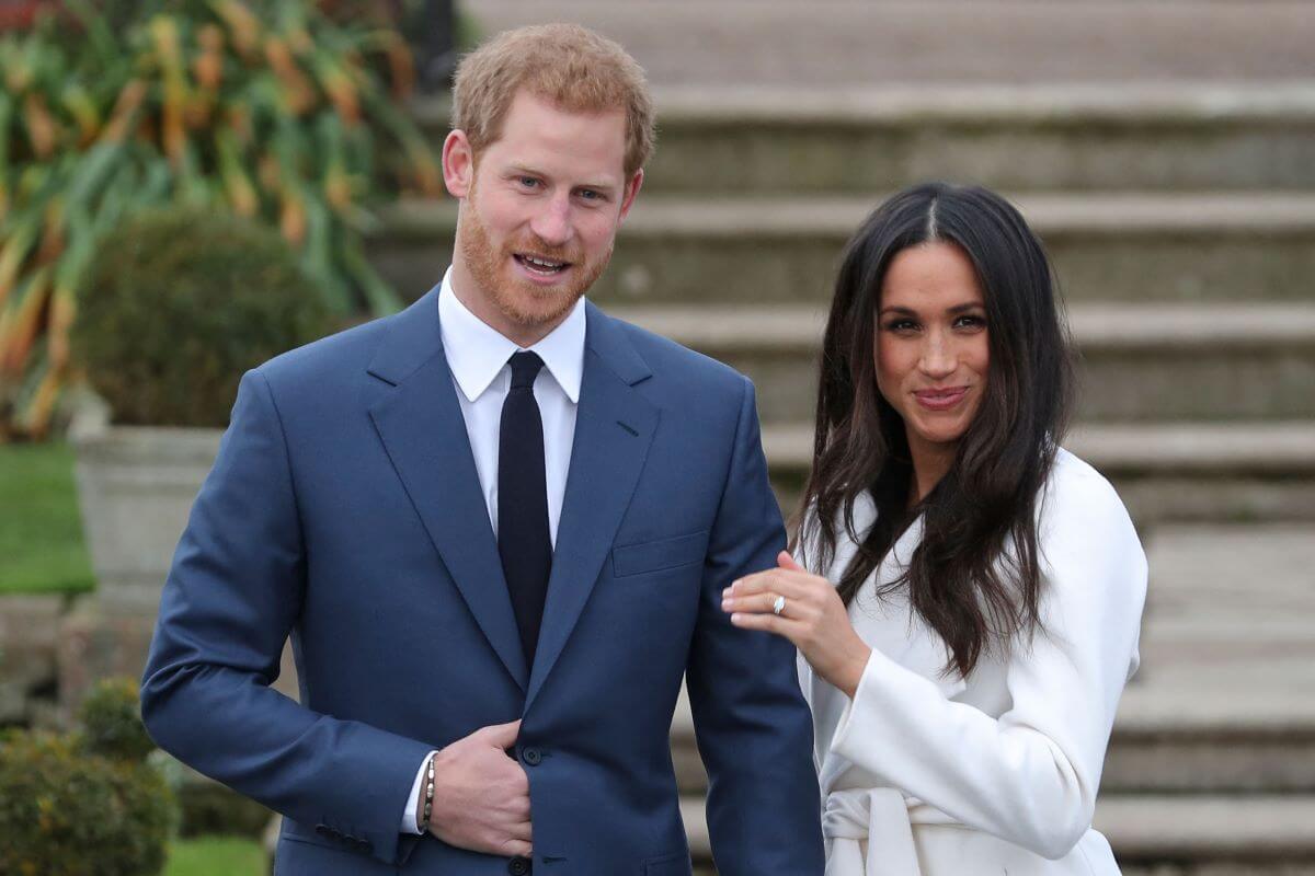 Meghan Markle shows off her engagement ring from Prince Harry while they pose for a photos in the Sunken Garden at Kensington Palace