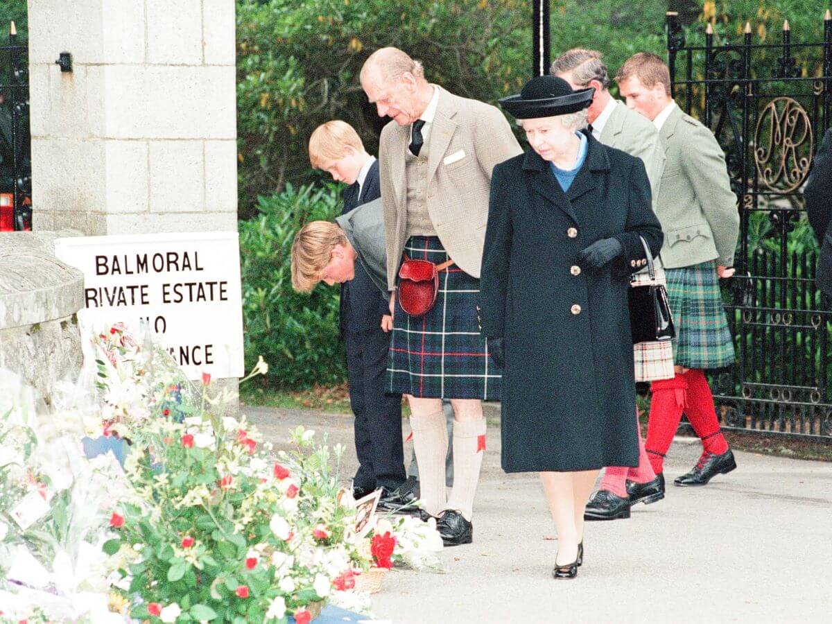 Members of the royal family stop to look at floral tributes left for Princess Diana at the gates of Balmoral Castle