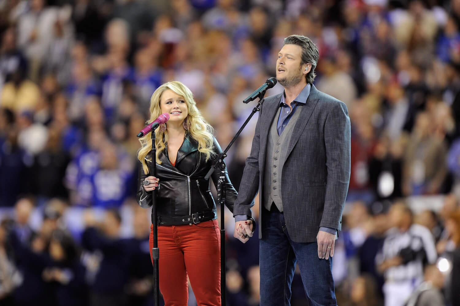 Miranda Lambert and Blake Shelton holding hands and performing in a stadium