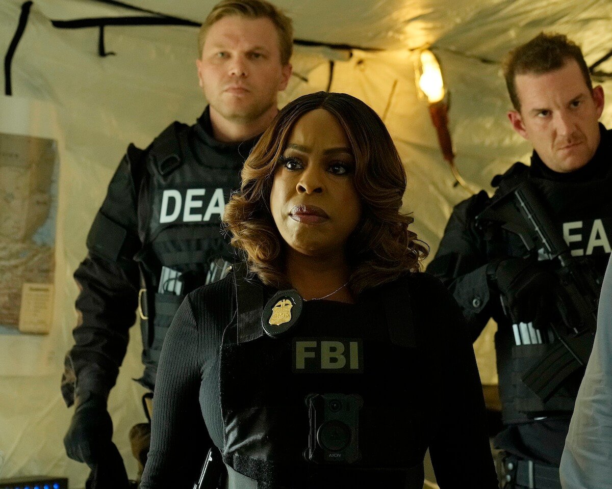 Niecy Nash-Betts, wearing a bulletproof FBI vest, standing in front of two DEA agents in 'The Rookie: Feds'