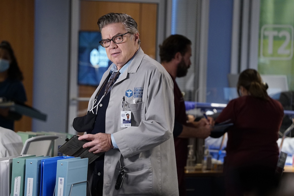 'Chicago Med' cast member Oliver Platt wearing a doctor's coat and glasses in a season 6 episode. 