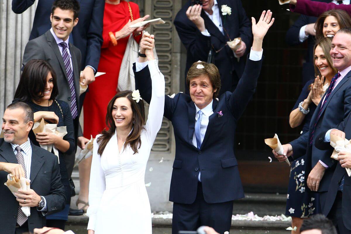 Paul McCartney and Nancy Shevell lift their joined arms into the air as they leave a registry office. 