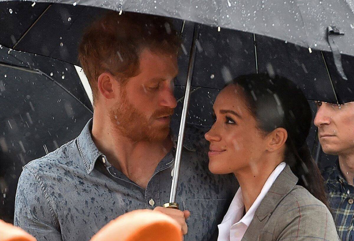 Prince Harry and Meghan Markle, who a commentator says 'runs rings around Harry for money,' watch aboriginal dances under an umbrella at Victoria Park