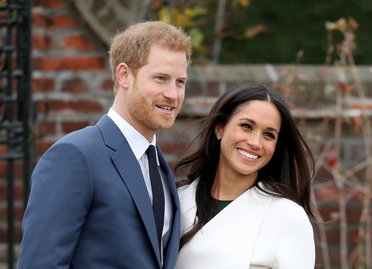 Prince Harry and Meghan Markle smiling and standing side-by-side.