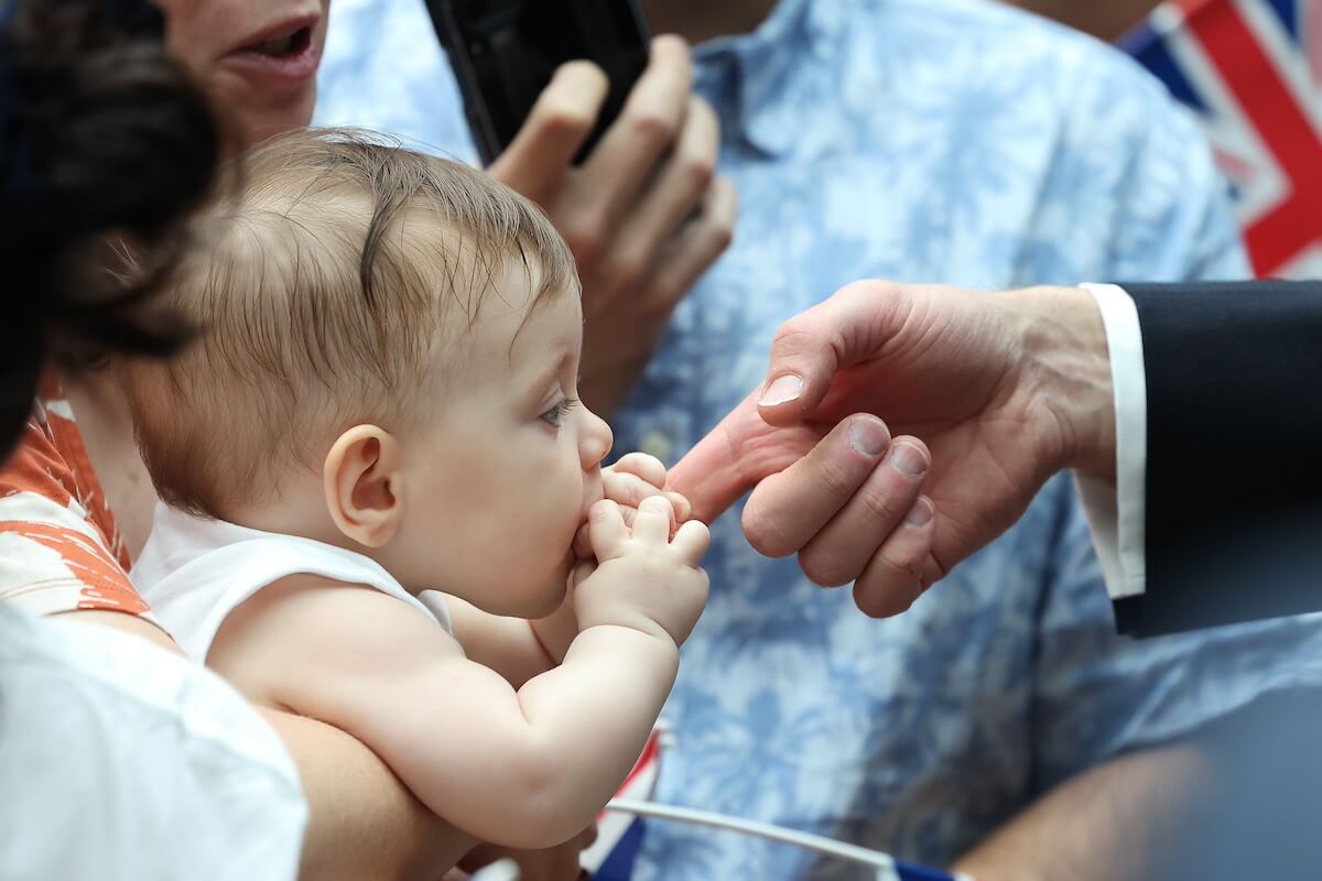 A baby bites Prince William's finger while the prince visits Singapore in 2023