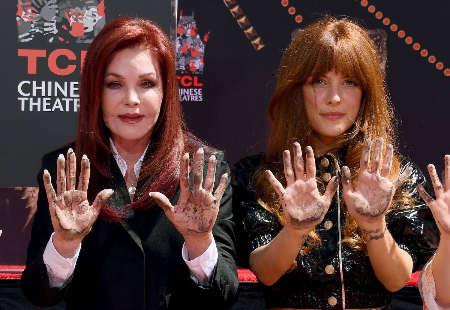 Priscilla Presley and Riley Keough holding their hands up at the Handprint Ceremony