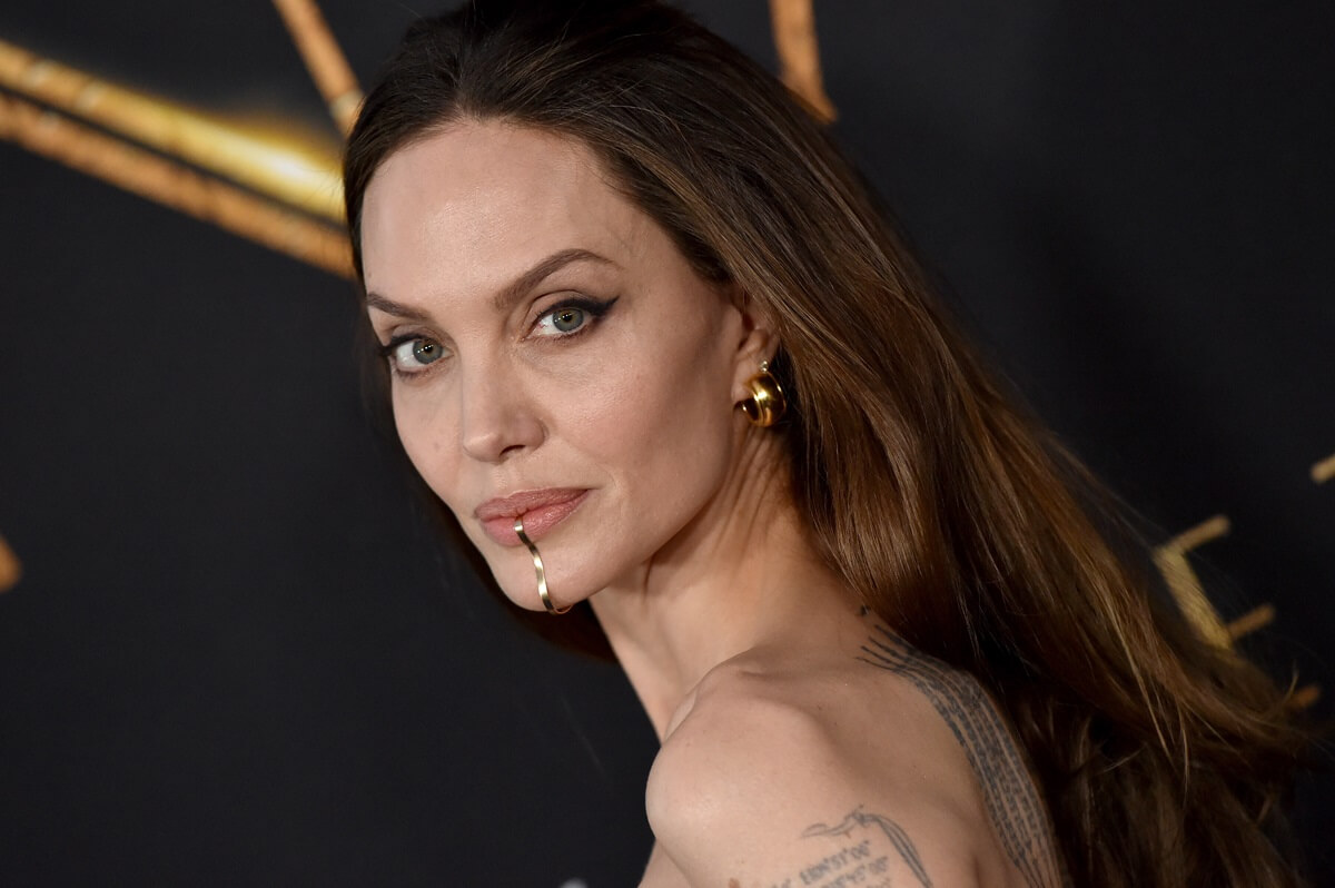 Angelina Jolie posing at 'The Eternals' premiere wearing a dress.