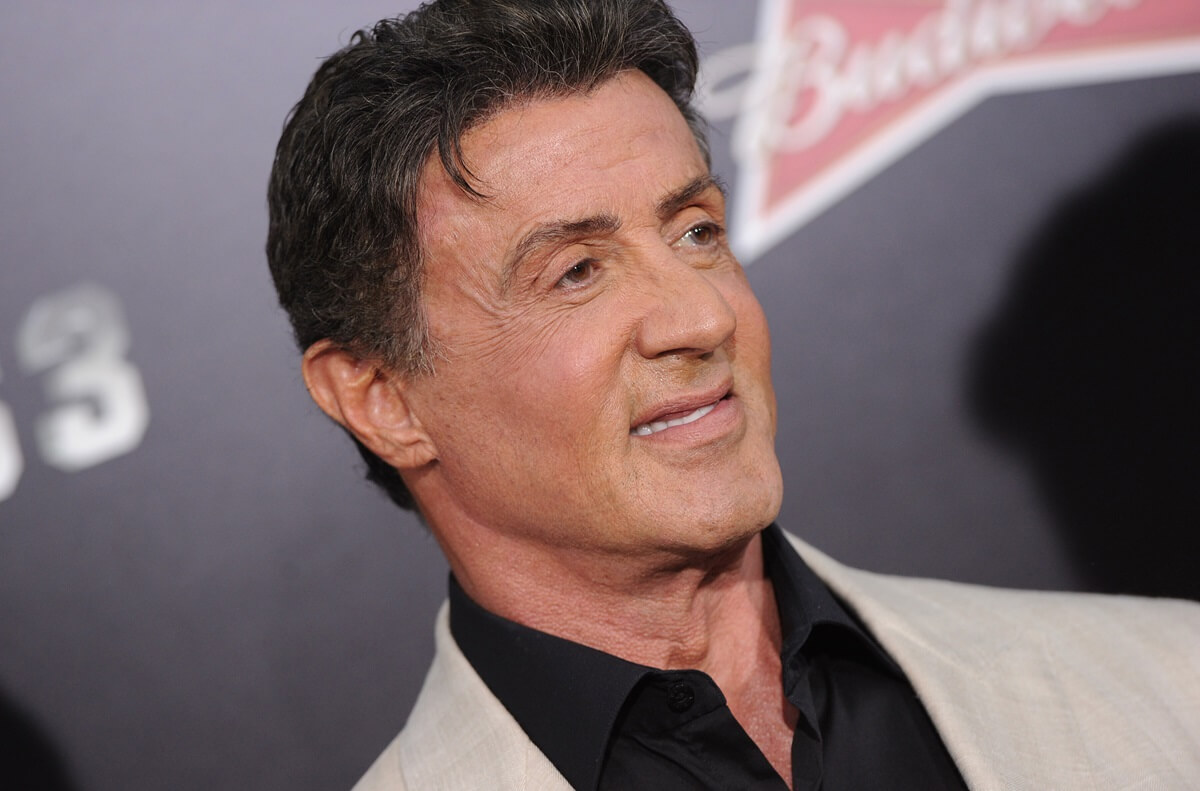 Sylvester Stallone posing in a white and black suit at 'The Expendables 3' premiere.
