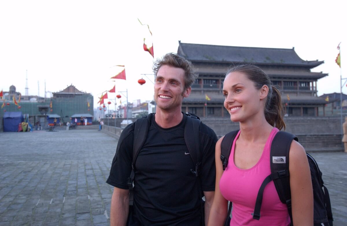 Smiling man and woman standing in front of the Xi'an Wall, China in an episode of 'The Amazing Race'