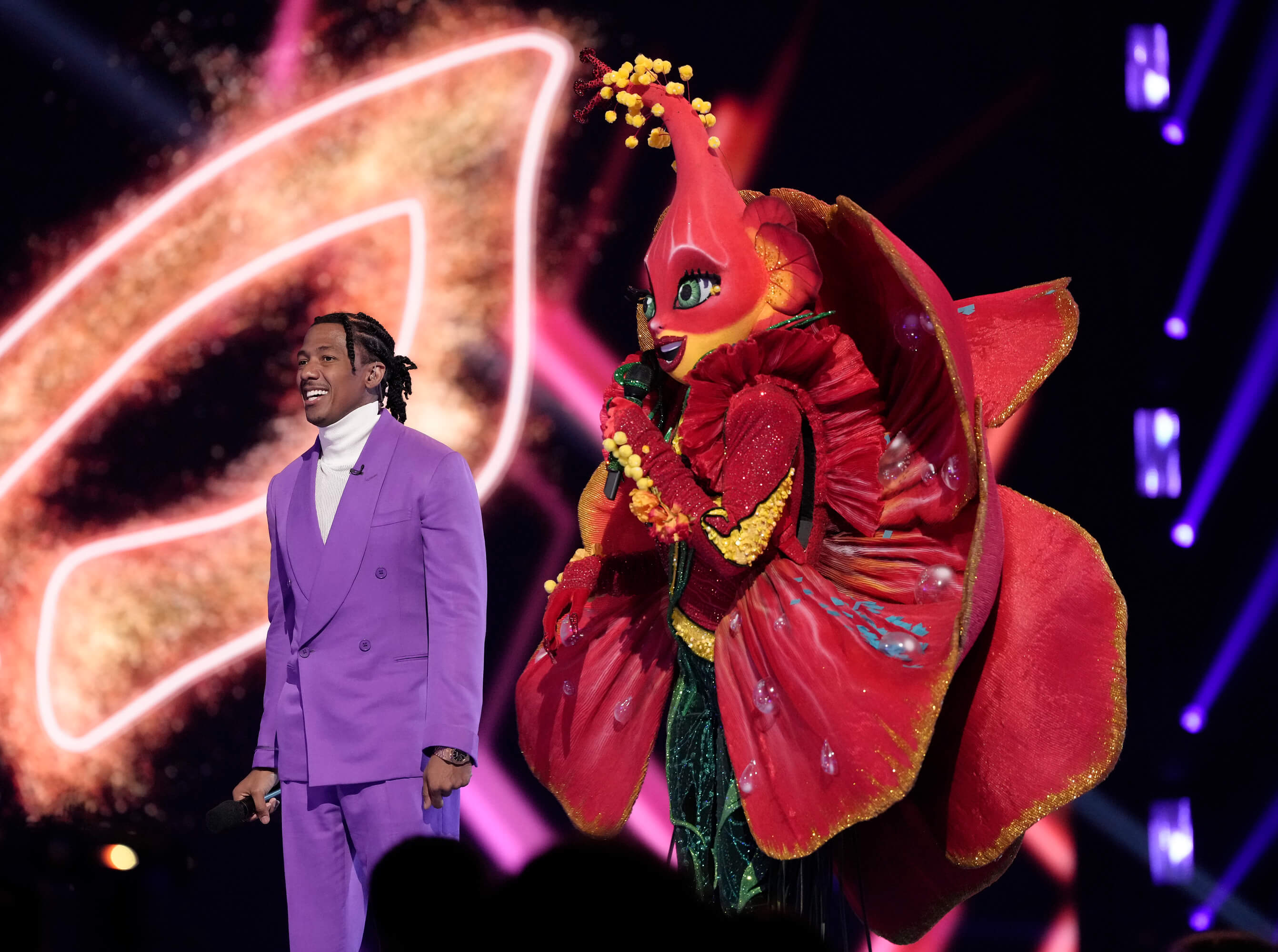 Hibiscus standing next to Nick Cannon in 'The Masked Singer' Season 10