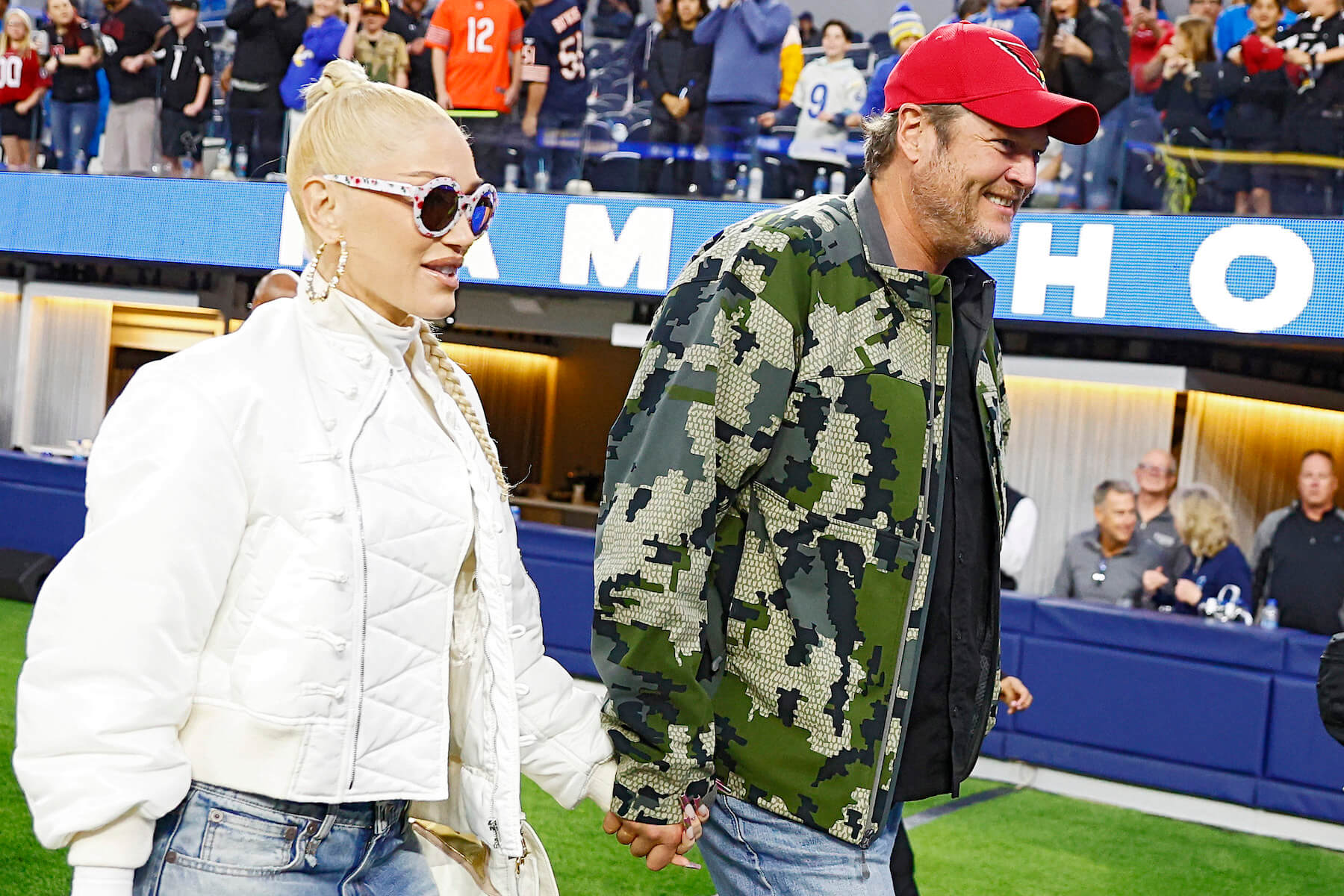 'The Voice' stars Gwen Stefani and Blake Shelton holding hands and walking across a football stadium