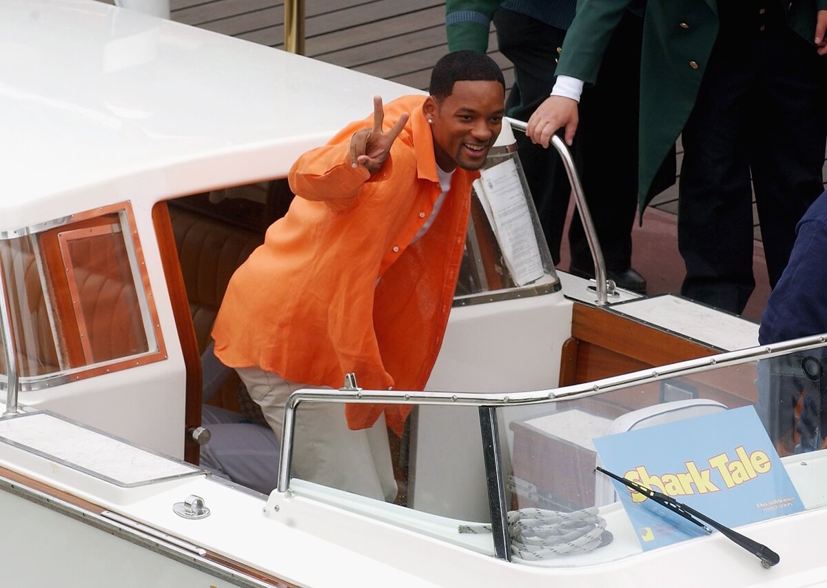 Will Smith posing in an orange shirt on a boat at a photocall for 'Shark Tale'.