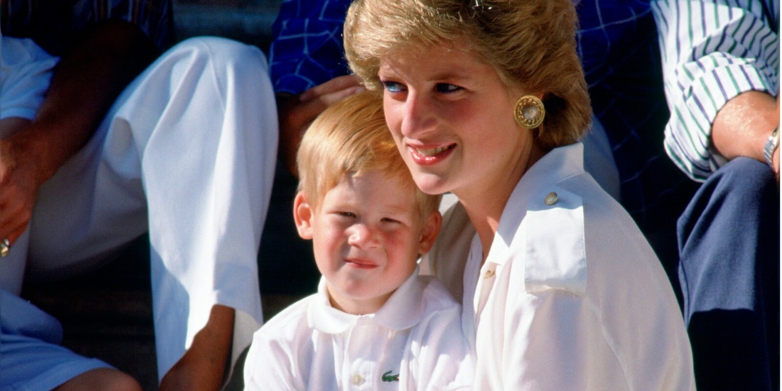 Prince harry sits on his mother' Princess Diana's lap, during a photocall with King Charles and Prince William.