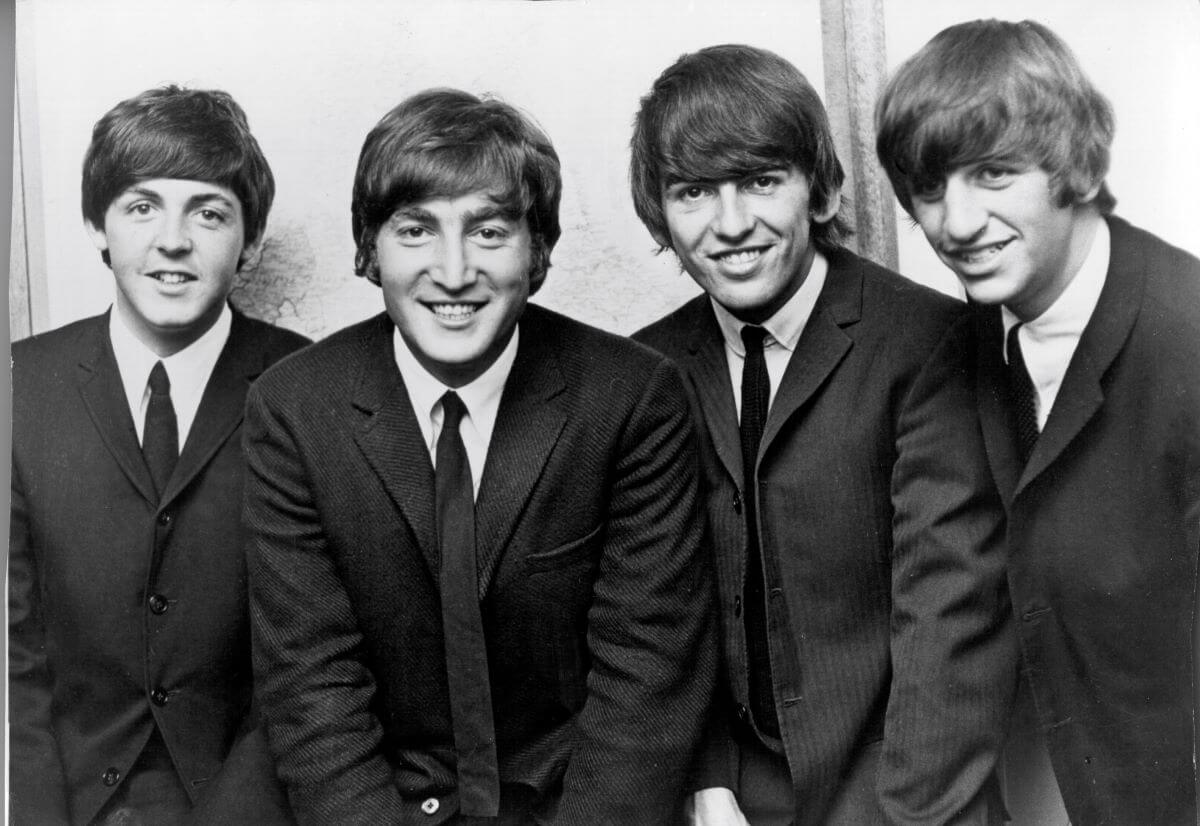 A black and white picture of Paul McCartney, John Lennon, George Harrison, and Ringo Starr of The Beatles wearing matching suits.