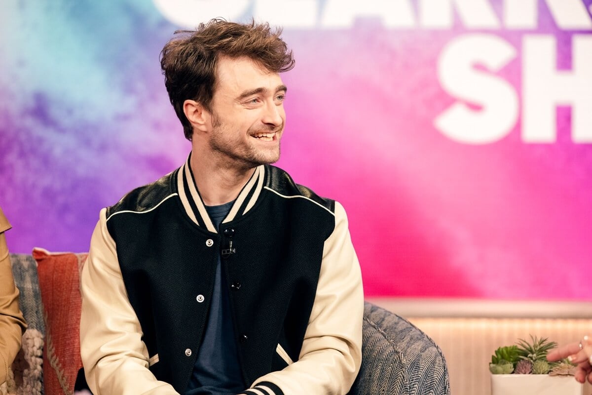 Daniel Radcliffe sitting down wearing a black and white jacket on the 5th season of the 'Kelly Clarkson Show'.