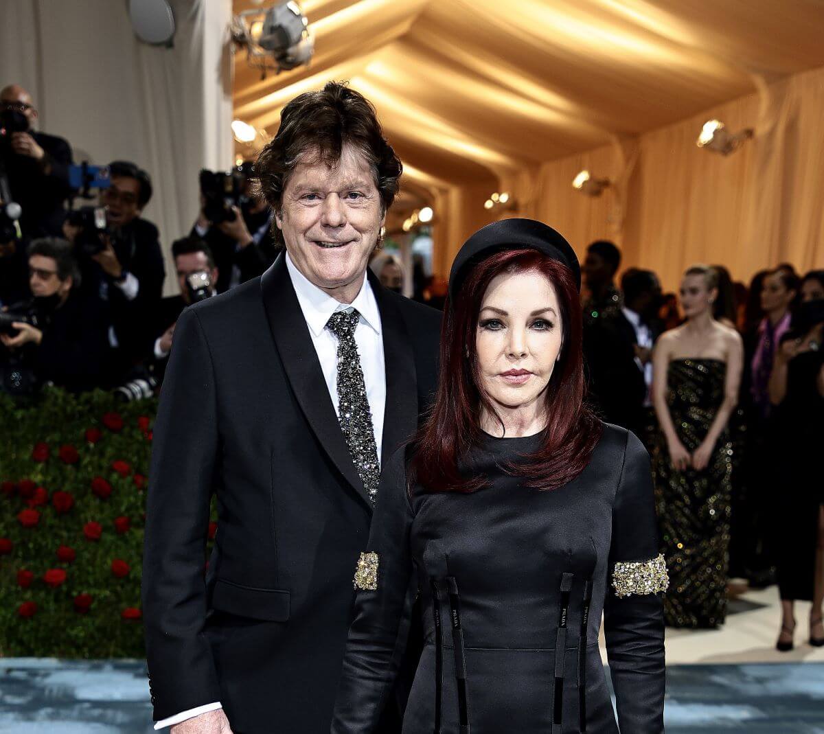 Jerry Schilling and Priscilla Presley wear black and stand on the carpet at the Met Gala.