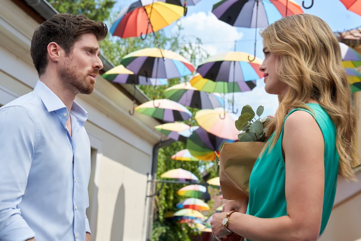 Marcus Rosner, and Ashley Newbrough standing under hanging umbrellas in Hallmark's 'Love on the Right Course'