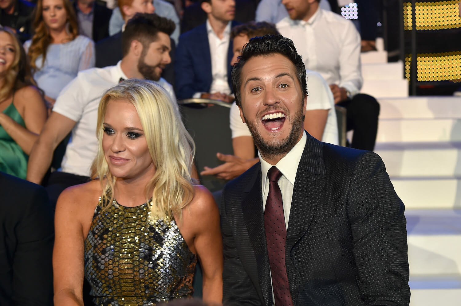 Luke Bryan smiling big while sitting next to his wife, Caroline Bryan, at the CMT Music Awards