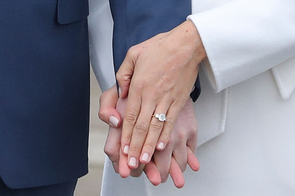 Meghan Markle shows off her engagement ring from Prince Harry whilst they pose for a photograph in the Sunken Garden at Kensington Palace