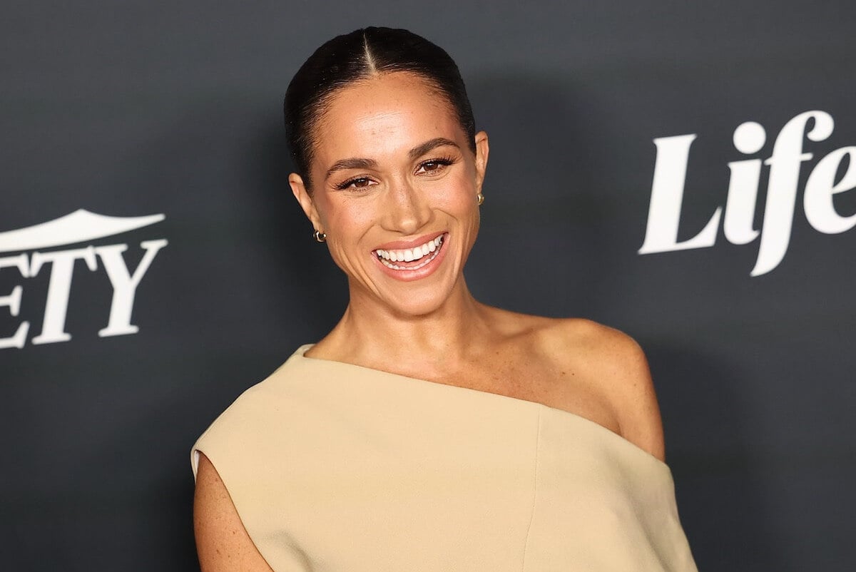 Meghan Markle, whose entrance into the royal family was like 'Princess Diana all over again,' according to 'Endgame' author Omid Scobie, smiles