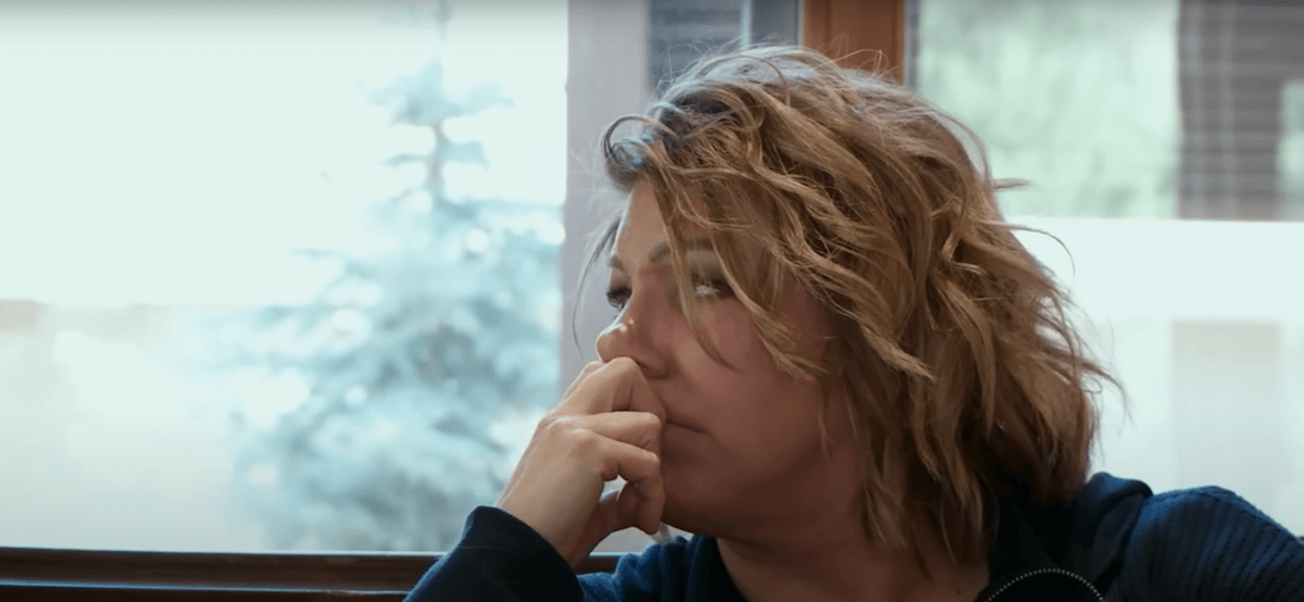 Meri Brown of 'Sister Wives' looking out a window with her hand on her mouth