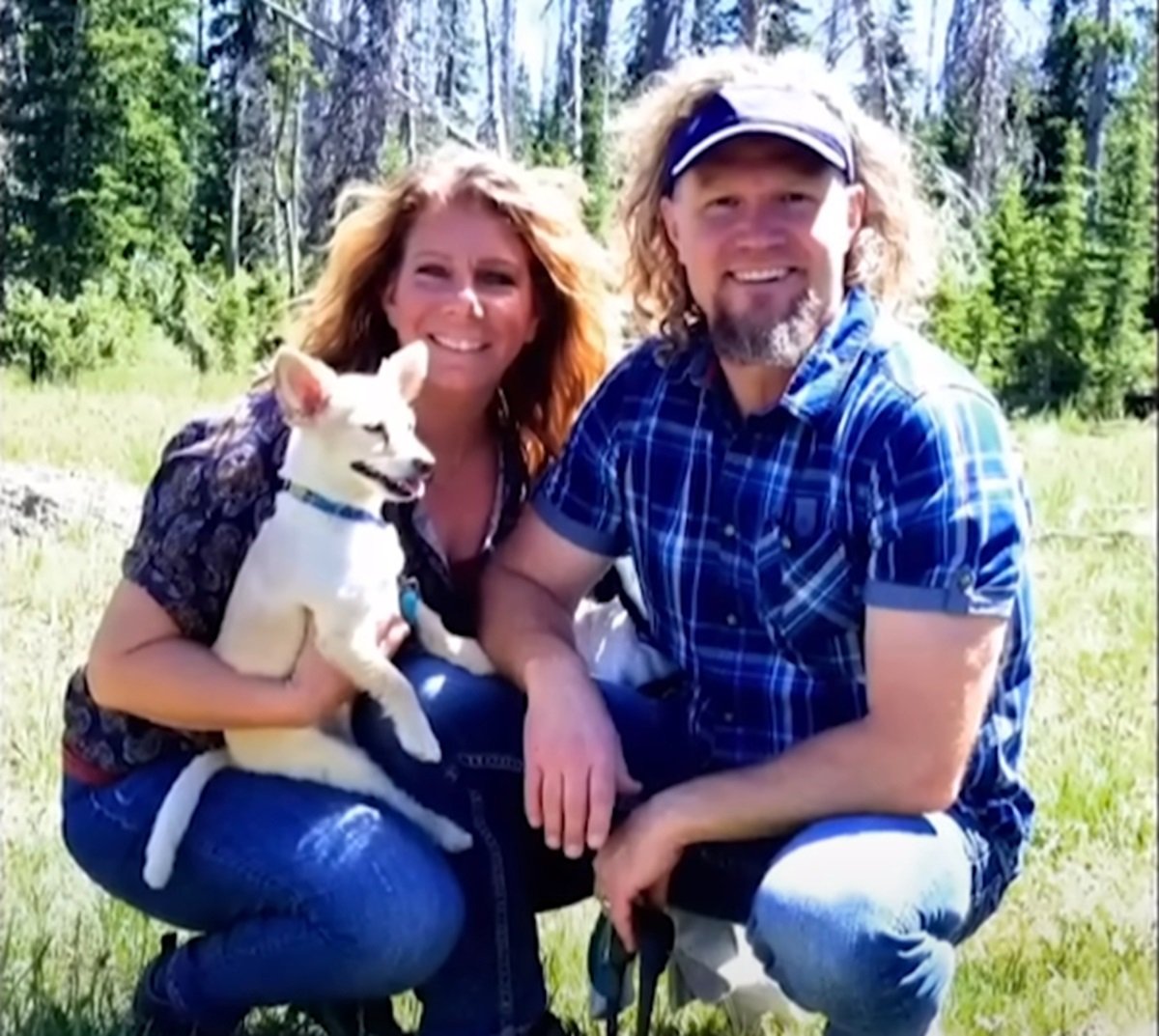 Meri Brown and Kody Brown pictured together outside with Meri holding her dog in front of a forest
