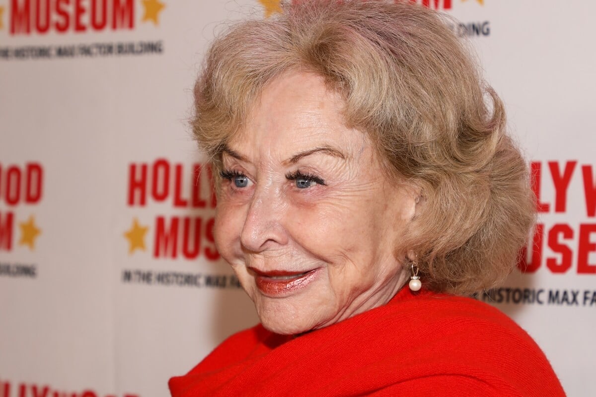 A closeup of Michael Learned in a red top at an event in 2023