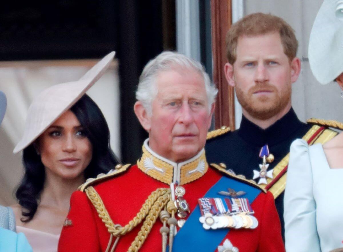 Now-King Charles III, Meghan Markle, and Prince Harry standing on the balcony of Buckingham Palace during Trooping The Colour 2018