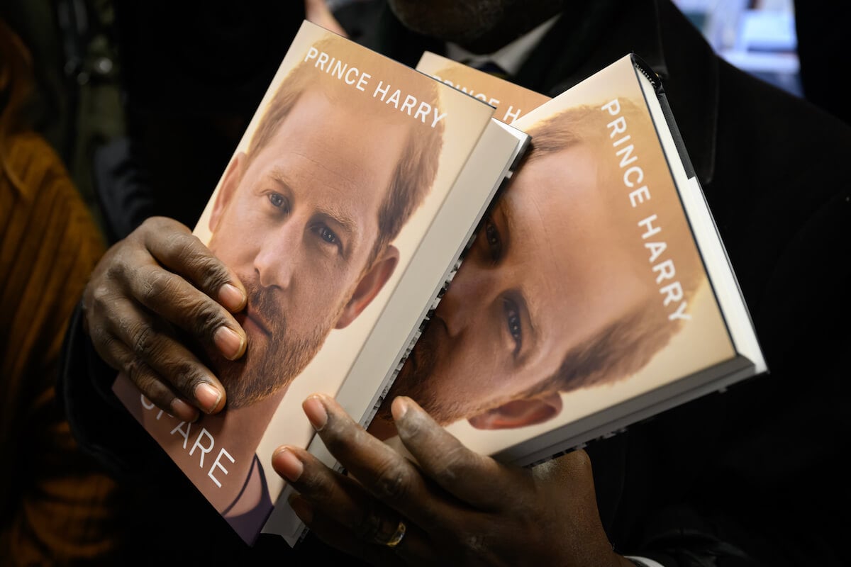 A person holds copies of Prince Harry's 'Spare' memoir, which, per Omid Scobie, isn't going to 'see the light of day' with a Part II