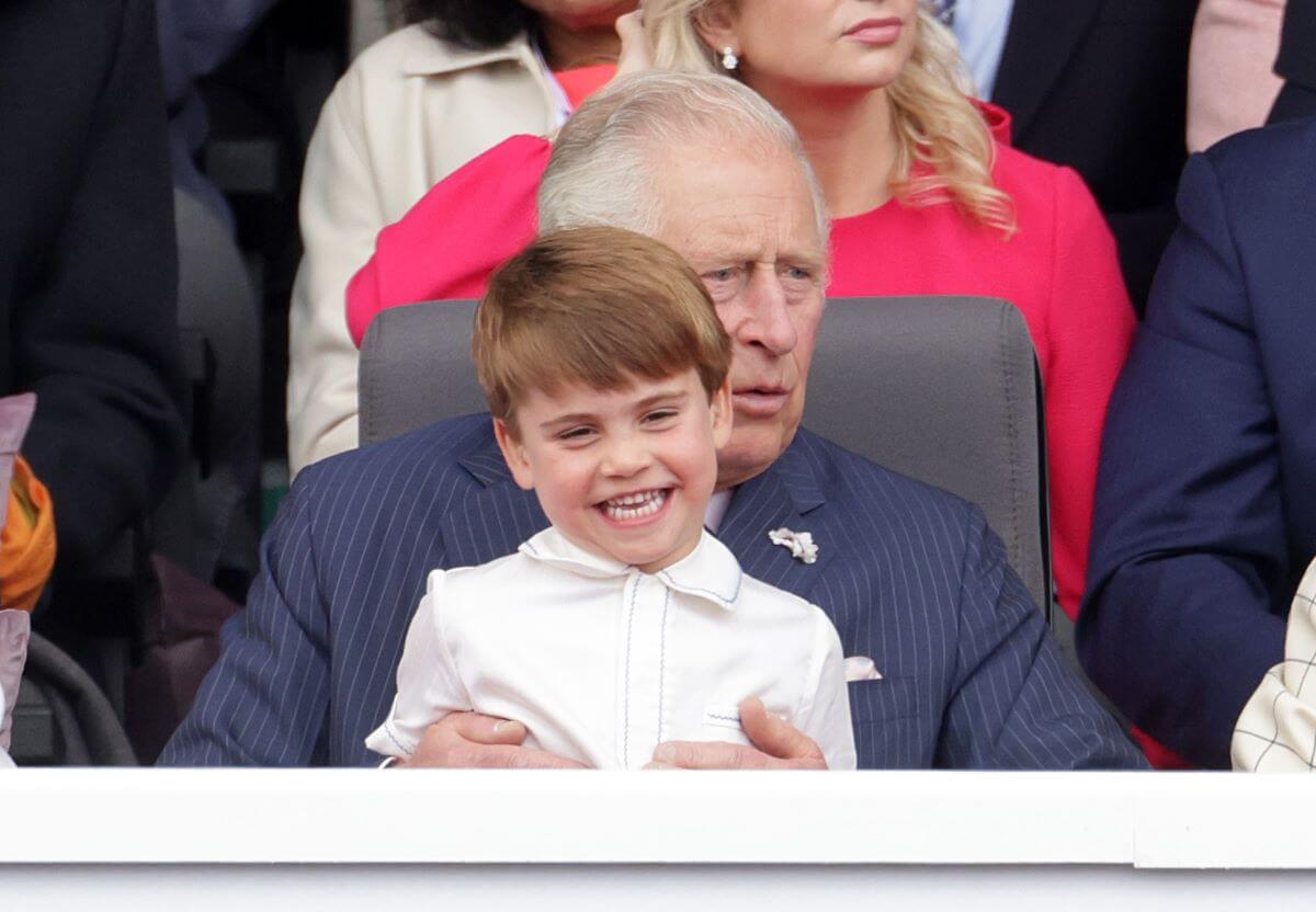 Prince Louis smiling as he sits on his grandfather Charles' lap during the Platinum Pageant