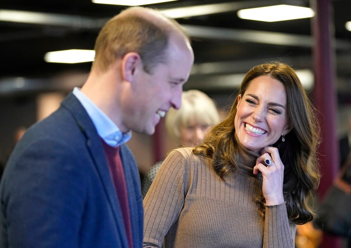 Prince William and Kate Middleton laughing as they stand next to each other.