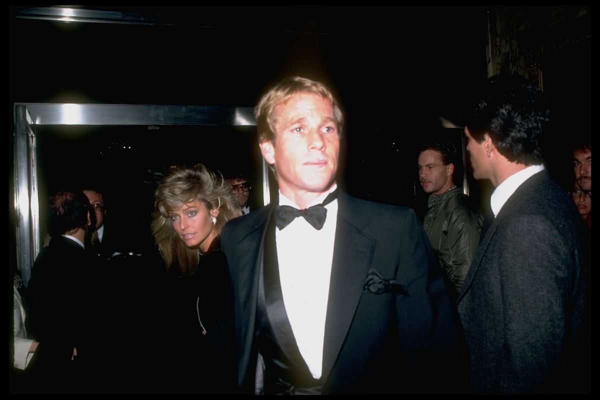 Ryan O'Neal, in a tux, with Farrah Fawcett in the background