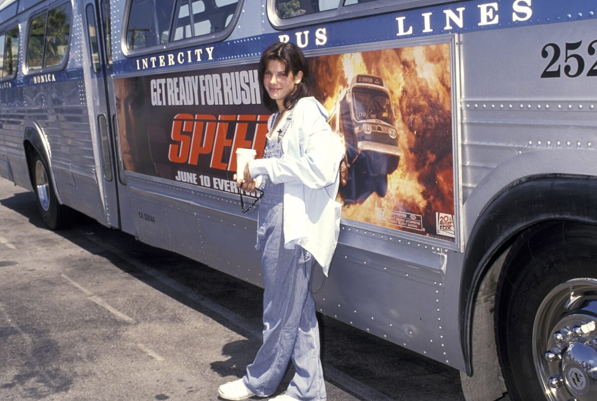 Sandra Bullock promoting 'Speed' while posing in front of a bus.