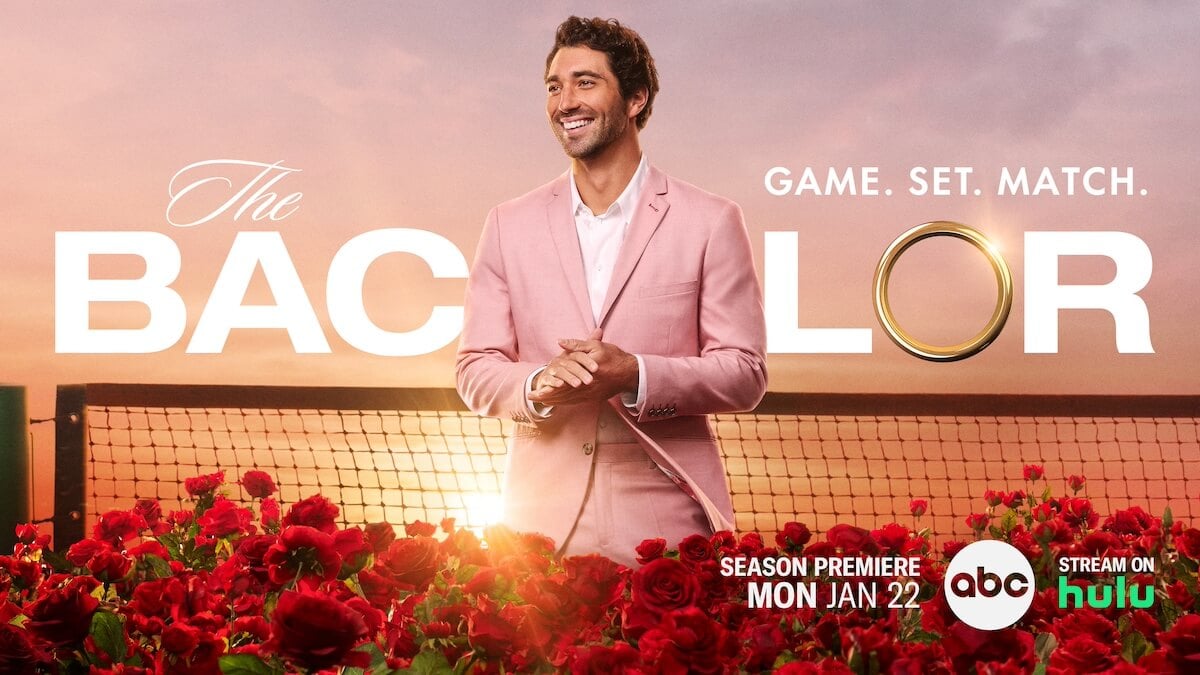 Joey Graziadei in a pink blazer in front of a tennis net in the key art for 'The Bachelor' Season 28
